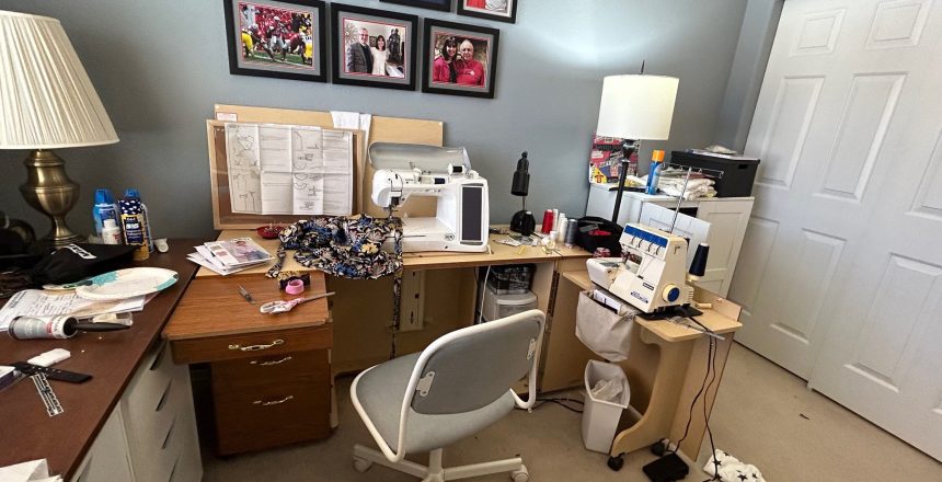 Sewing room with machine, patterns, fabric, and framed photos on the wall.